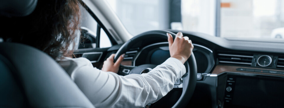 Hands on steering wheel. Beautiful businesswoman trying her new car in the automobile salon